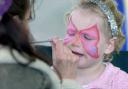 A little girl has her face painted.