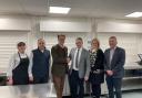 At the school kitchen at Ysgol Calon Cymru’s Llandrindod Well campus, Powys County Council’s Cabinet Member for a Connected Powys, Cllr Jake Berriman (third from left) shakes hands with Matt Lewis, Managing Director at Castell Howell
