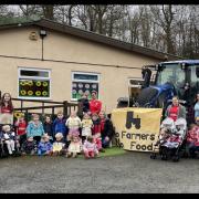 Country Kids Childcare children and staff pose for a picture. Pinned to the tractor is a banner that reads ‘No Farmers No Food’.