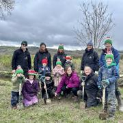 Local children with Urdd and Woodland Trust volunteers planting trees on 2024’s Urdd Eisteddfod site.
