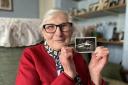 Ruth Davies, aged 77, holds a photo of herself in a pram.