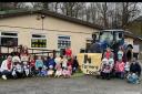 Country Kids Childcare children and staff pose for a picture. Pinned to the tractor is a banner that reads ‘No Farmers No Food’.