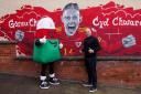 Wales manager Rob Page with Mistar Urdd standing in front of the Connor Roberts mural outside Charlies store in Newtown,