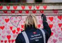 A volunteer from the Covid-19 Bereaved Families for Justice campaign group paints a heart on the National Covid Memorial Wall opposite the Palace of Westminster in central London, which remembers people who have died of the virus. Picture date: Friday