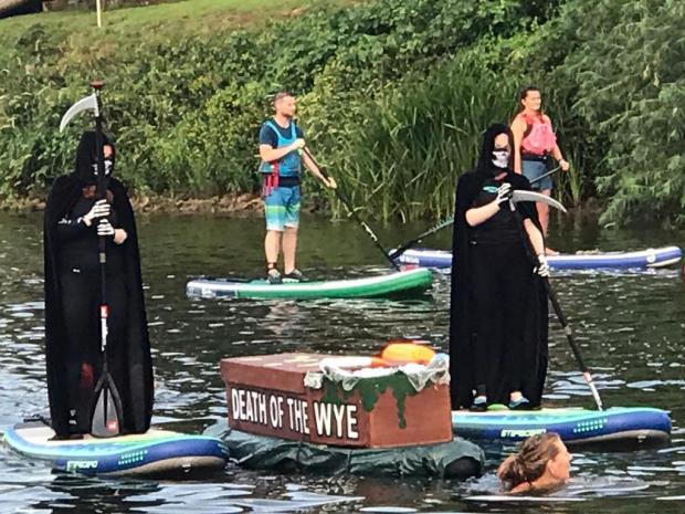 County Times:  Wild swimmer Angela Jones tows a floating coffin down the River Wye in 2021, with the slogan 'Death of the Wye', accompanied by grim reapers on paddle boards, to highlight the declining health of the Wye
