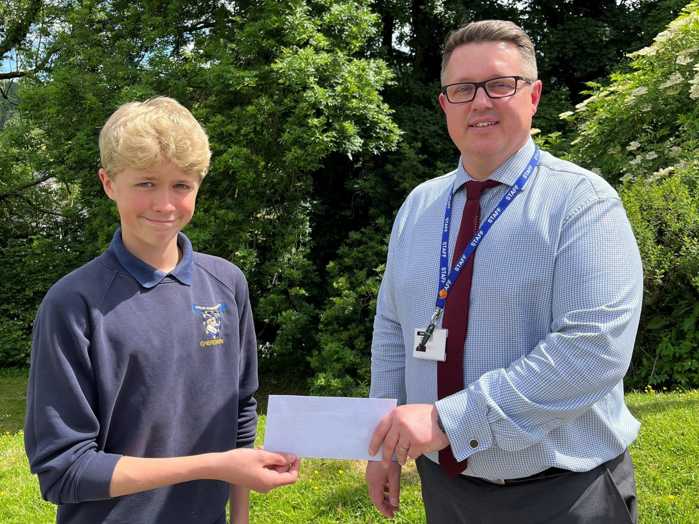 Alaw Francis, 14, whose winning design forms the basis of the new Ysgol Bro Caereinion logo, is presented with his prize by Huw Lloyd-Jones, Headteacher of Ysgol Bro Caereinion.