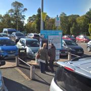 People paying at a machine in the pay and display car park in Back Lane, Newtown