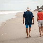Retired people walking on a beach.