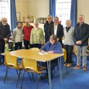 Rev Hermione Morris signing contract supported by Friends of St Myllin's Church.