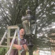 Andy Green cleaning a streetlight in St Myllin's Church, Llanfyllin.