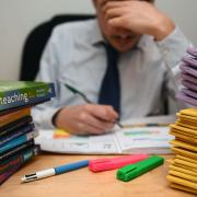 File photo dated 05/03/17 of a teacher next to a pile of classroom books. Teachers in England miss more than 50,000 days a week due to illness, which education unions say supply agencies exploit to 